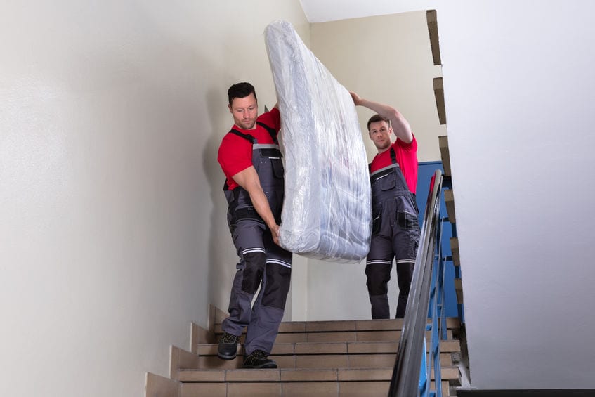 Young Men In Uniform Carrying Mattress Downward